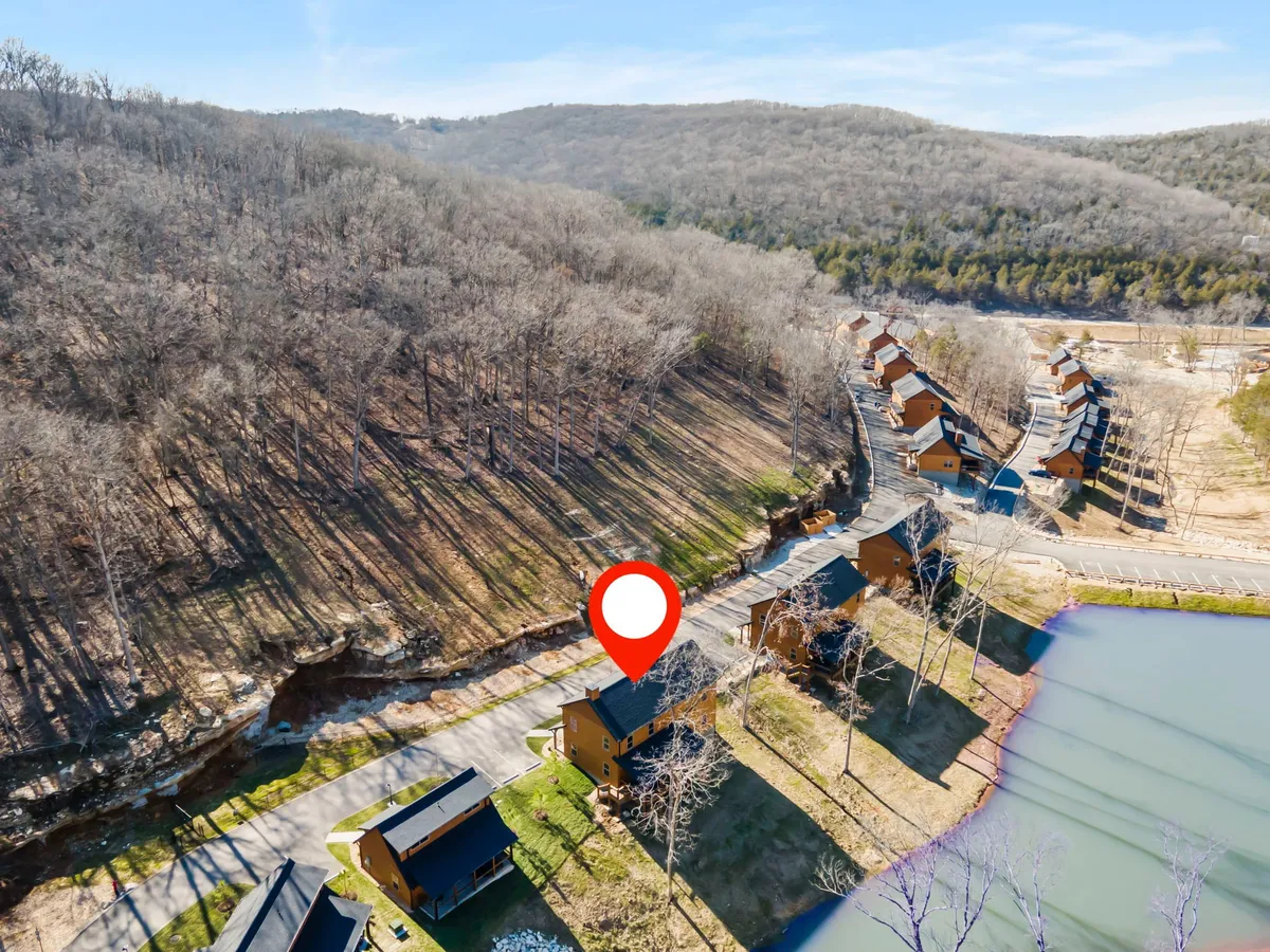 A peaceful lakeside scene featuring a charming cabin nestled among trees, with the lake's calm waters reflecting the sunrise. The setting highlights opportunities for hiking, fishing, picnicking, and relaxing by the water, surrounded by the natural beauty of the Ozarks.