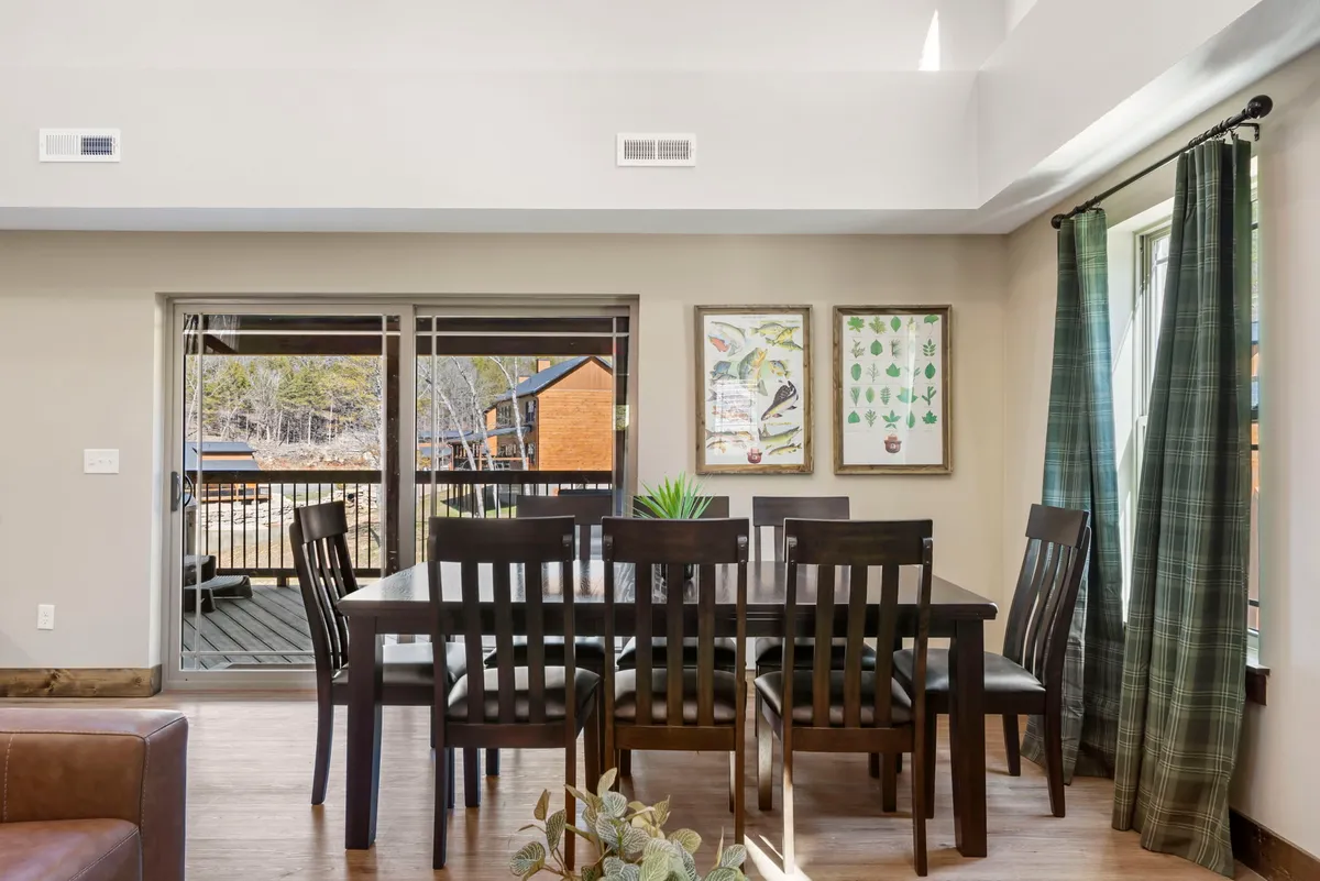 A welcoming dining area with a large table surrounded by chairs, wall art, and windows allowing in natural light. The setting is perfect for shared meals, story-swapping, and planning adventures, capturing the spirit of togetherness.